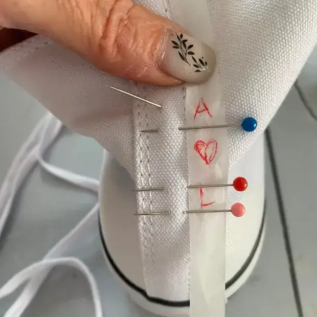 Hand-embroidered personalised initials being pinned onto canvas shoes