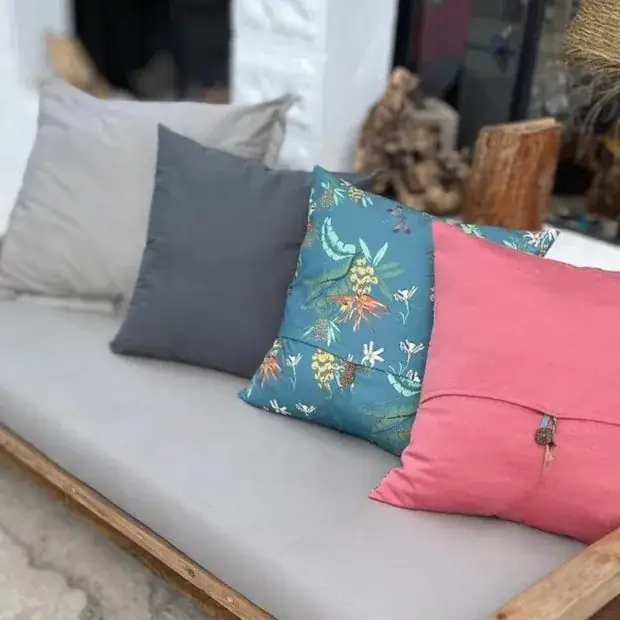 Handmade scatter cushions in grey, charcoal, teal floral and pink on an outdoor sofa