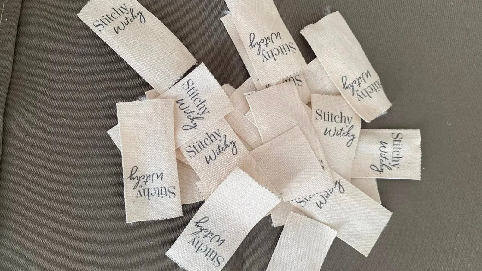 Handwoven Stitchy Witchy labels scattered on grey fabric
